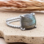 Silver ring with a large labradorite stone on a textured surface