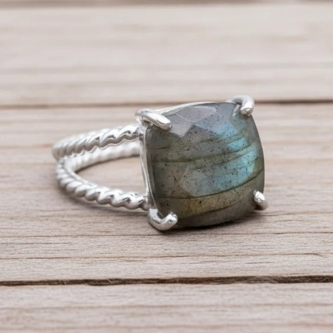 Silver ring with a large labradorite stone on a textured surface