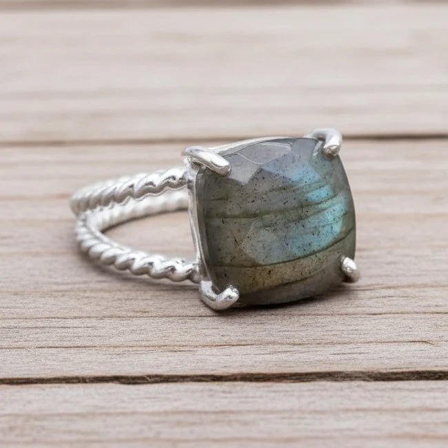 Silver ring with a large labradorite stone on a textured surface