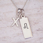 sterling silver initial x leo zodiac star sign pendant necklace against a light wooden background