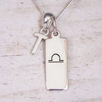 Silver Initial and Libra Zodiac Necklace with a letter T pendant and engraved Libra bar, flat lay on light wood
