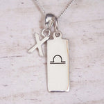 Silver Initial and Libra Zodiac Necklace with a letter X pendant and engraved Libra bar, flat lay on light wood