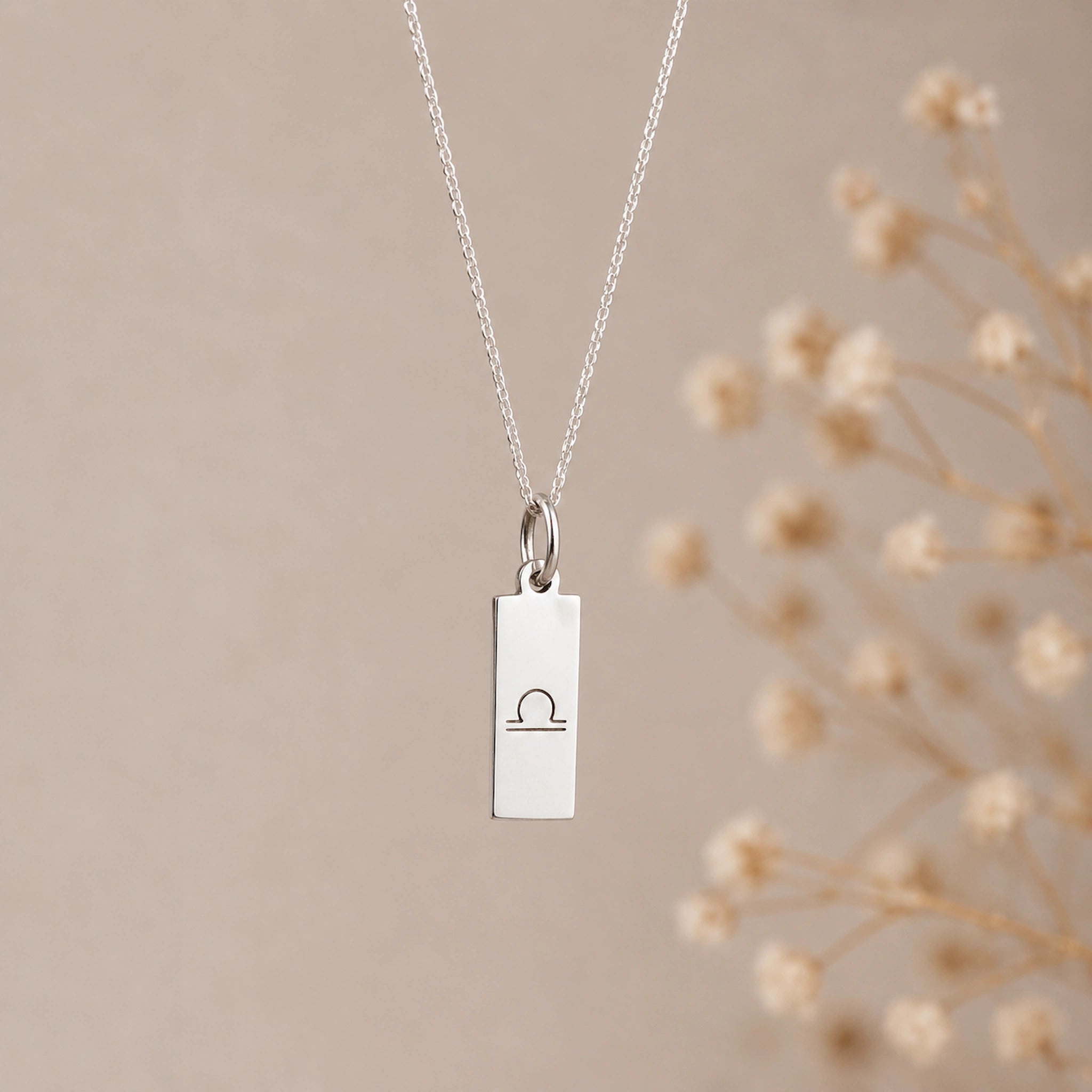 925 sterling silver Libra necklace with a minimalist libra zodiac sign line glyph engraved rectangular pendant on a fine chain against a light background