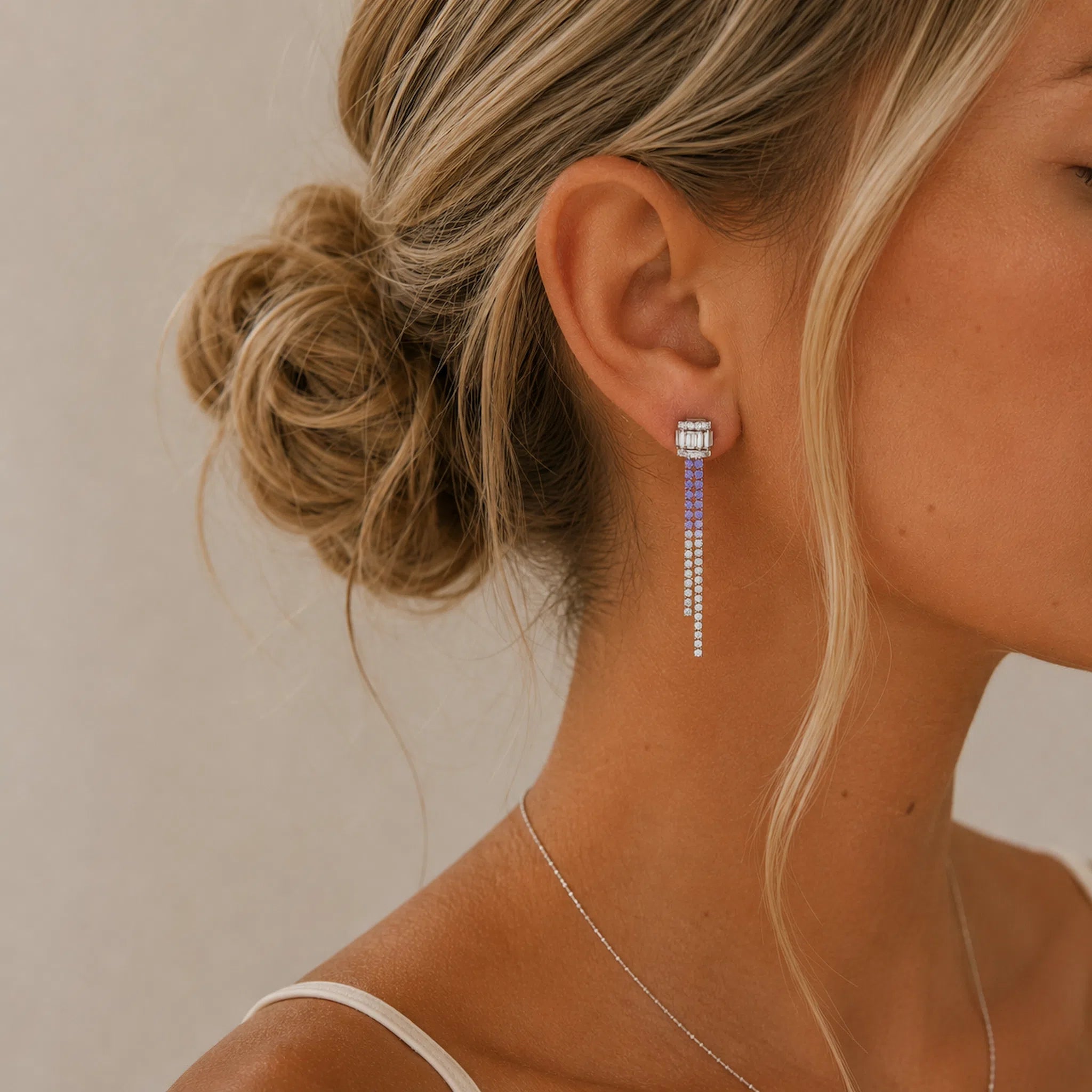Close-up of a woman wearing silver lilaz CZ ombre earrings with a neutral background