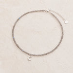 dainty natural labradorite beaded necklace with a silver crescent moon charm on a white background.