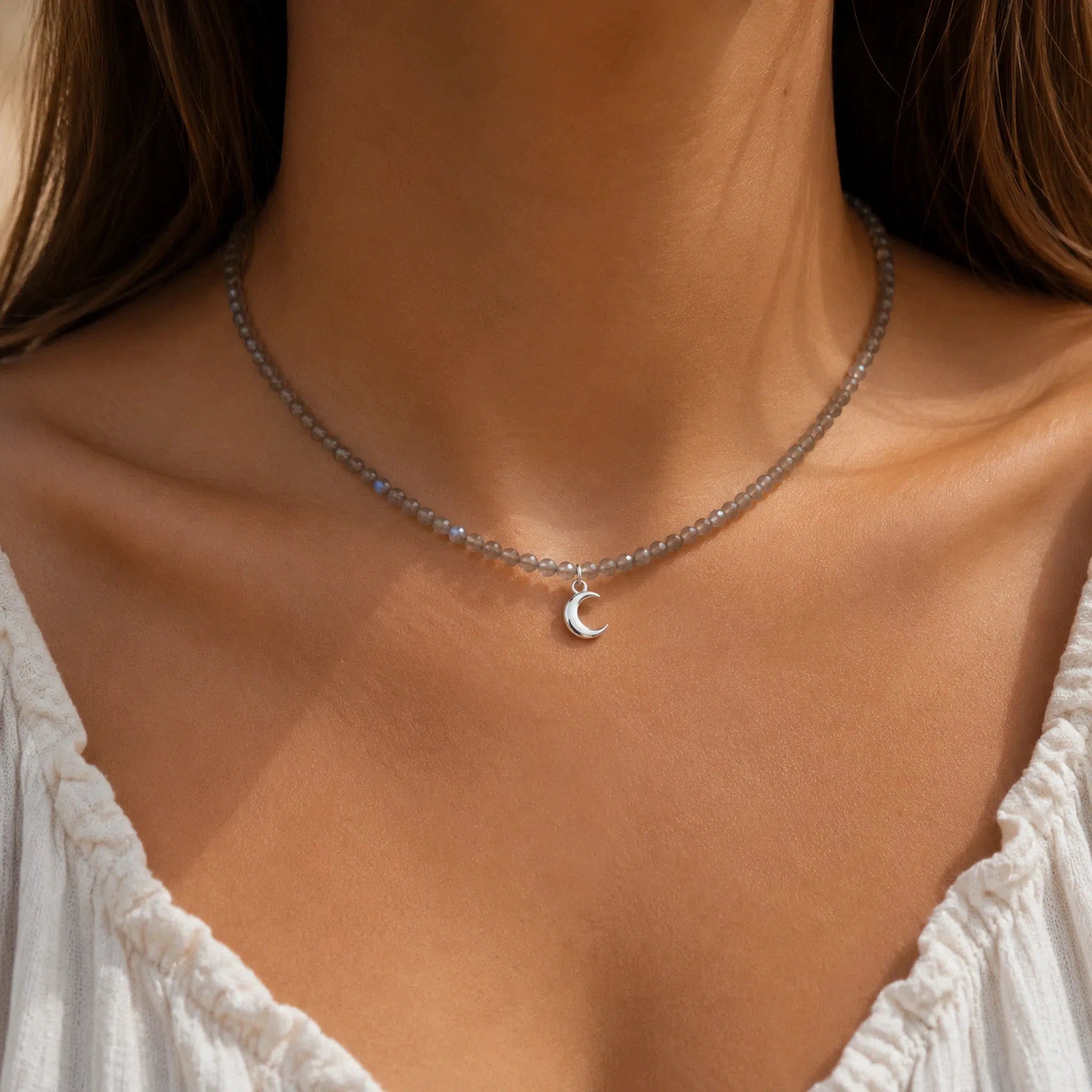 woman wearing a natural labradorite beaded choker necklace with a silver crescent moon charm.