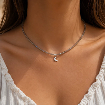 woman wearing a natural labradorite beaded choker necklace with a silver crescent moon charm.