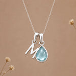 Sterling silver M initial necklace with pale blue March aquamarine in a polished teardrop bezel