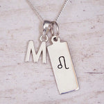 sterling silver initial m leo zodiac star sign pendant necklace against a light wooden background