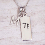 sterling silver initial m virgo zodiac star sign pendant necklace against a light wooden background
