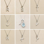 Collection of silver necklaces with letter pendants R to Y on a beige background, as personalised initial options for a March Birthstone Aquamarine Necklace.