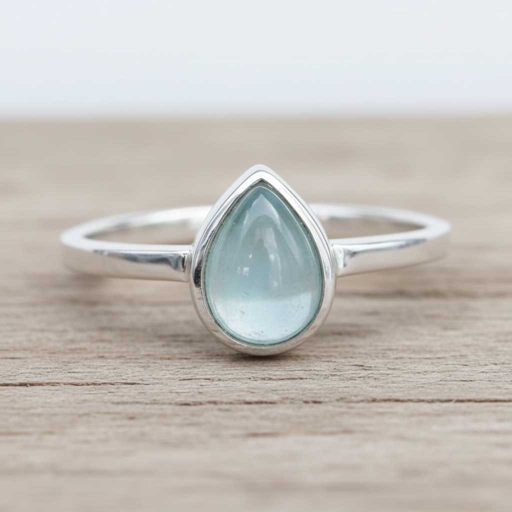 Sterling Silver ring with a teardrop-shaped light blue natural aquamarine gemstone on a wooden surface