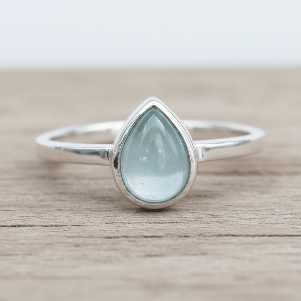 Sterling Silver ring with a teardrop-shaped light blue natural aquamarine gemstone on a wooden surface