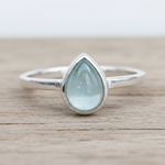Sterling Silver ring with a teardrop-shaped light blue natural aquamarine gemstone on a wooden surface