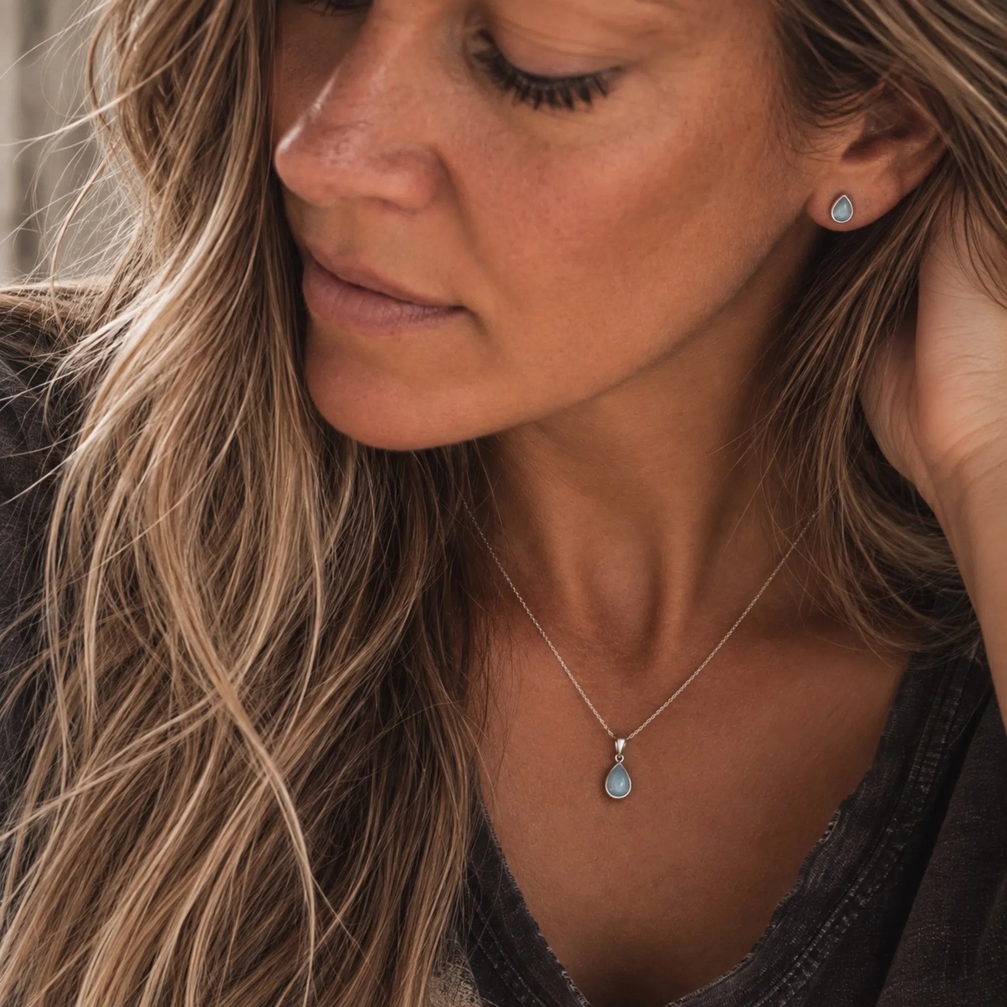 model wearing sterling silver march birthstone jewellery set of dainty natural aquamarine pendant necklace and matching stud aquamarine earrings