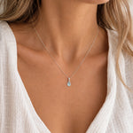 close up of a woman wearing a sterling silver march birthstone necklace with a pear shaped natural aquamarine pendant
