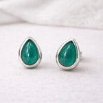 Teardrop-shaped may birthstone green natural emerald gemstone earrings with sterling silver settings on a white background