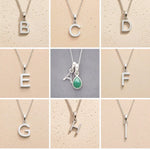 Collage of silver necklaces with letters A to H on a beige background, as personalised initial pendant options to add to a May Birthstone Emerald Necklace.