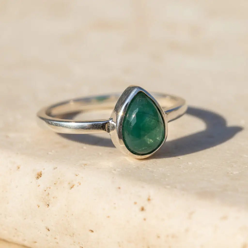sterling Silver ring with a may birthstone green emerald teardrop-shaped gemstone on a light surface