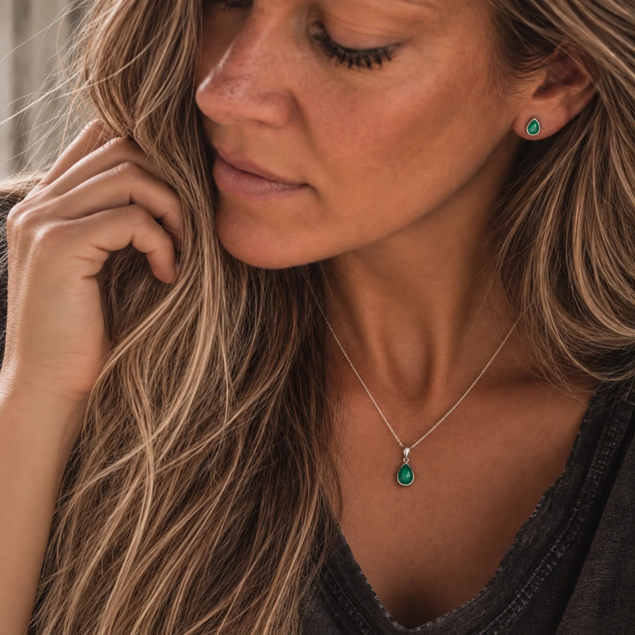 model wearing sterling silver may birthstone jewellery set of dainty natural emerald pendant necklace and matching stud emerald earrings