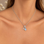Woman wearing a sterling silver A initial and natural November blue topaz necklace