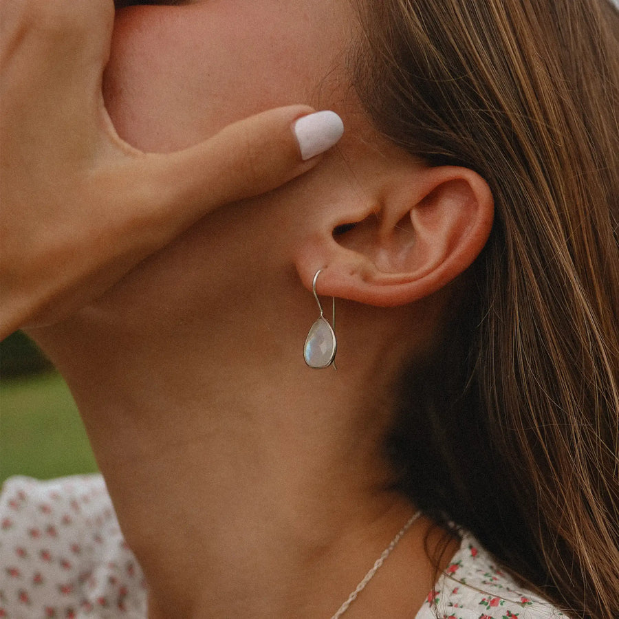 Woman's profile, showing a moonstone drop earring in the shape of a teardrop.
