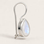 A silver-toned teardrop pendant with a faceted iridescent moonstone inlay, suspended from a curved silver wire loop, shown on a light beige background.