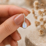 sterling silver moonstone earrings featuring pear-shaped natural moonstones faceted and bezel set with french hook style being held