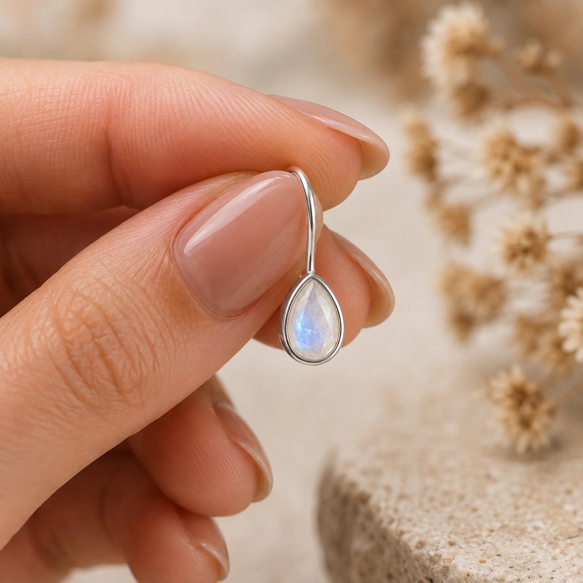 sterling silver moonstone earrings featuring pear-shaped natural moonstones faceted and bezel set with french hook style being held