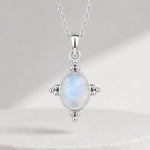 A sterling silver pendant necklace featuring an oval-shaped iridescent moonstone with blue and white play-of-color, set in a four-pronged silver bezel on a delicate chain.