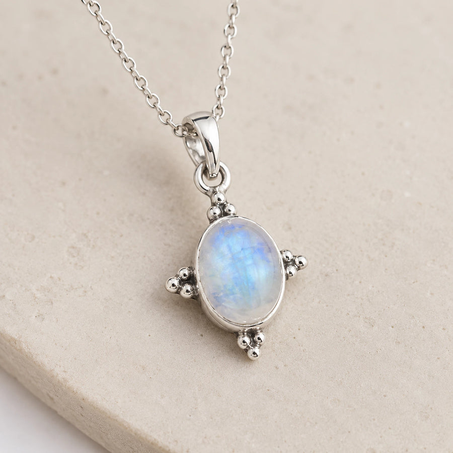 Oval moonstone pendant with blue and white flashes in a sterling silver four-point setting