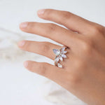 Hand wearing silver rings with a teardrop-shaped moonstones gemstone on a light background