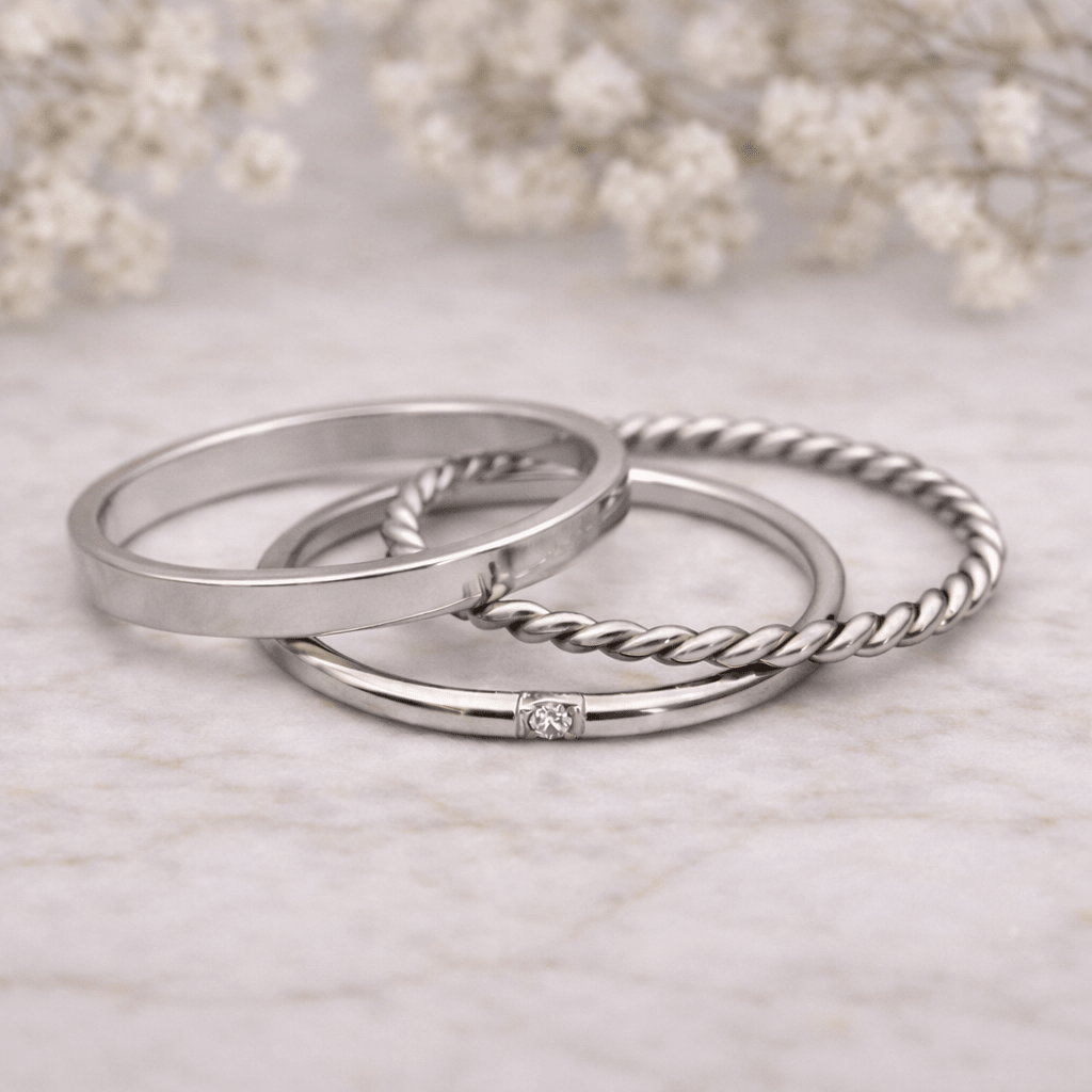 Three silver rings with various designs on a light background