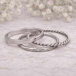 Three silver rings with various designs on a light background