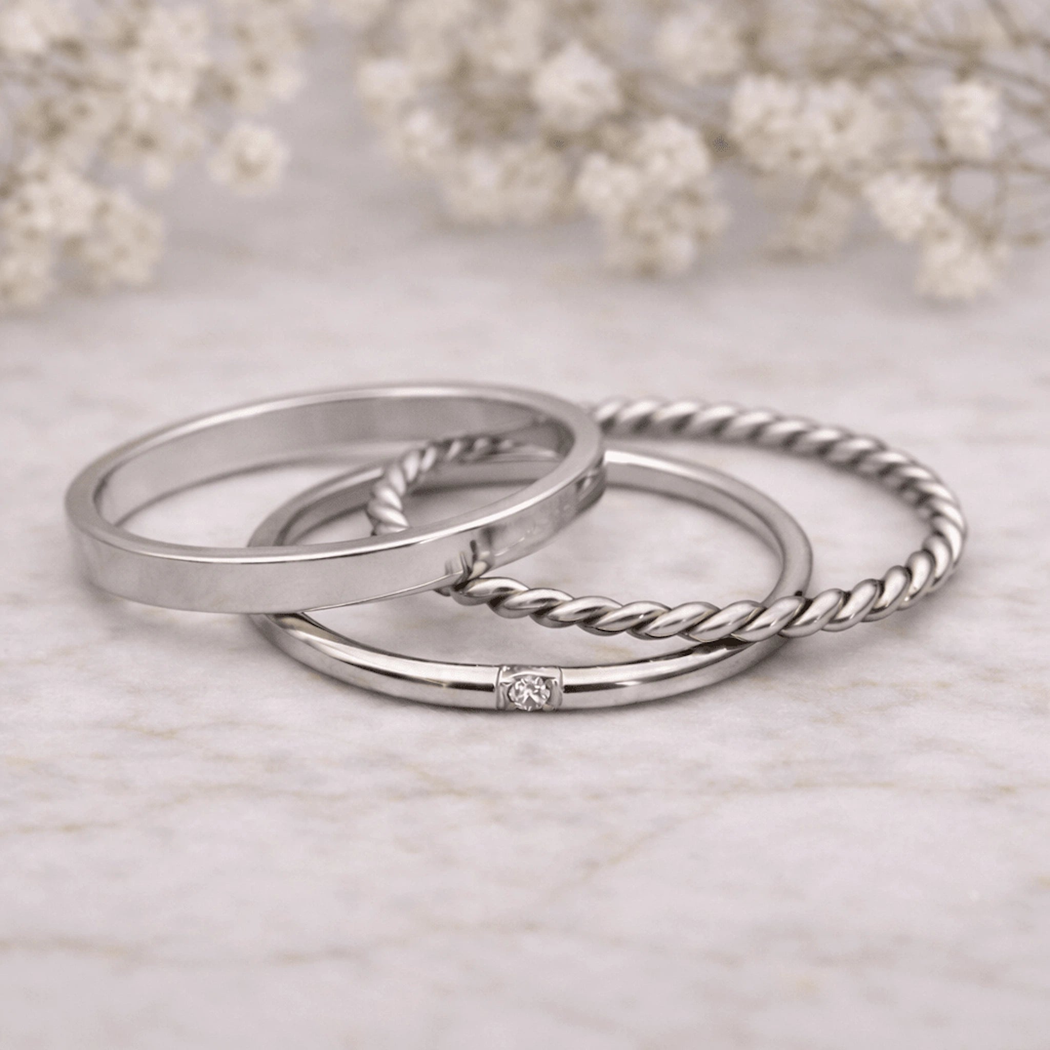 Three silver stacker rings with various designs on a light background
