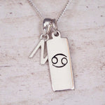 Sterling Silver N Initial Cancer Zodiac Star Sign Necklace on a fine silver chain against a light wooden background