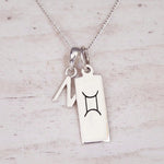 Sterling silver N initial and GeminI Necklace on a fine silver chain on a light wooden background
