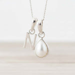 Sterling Silver necklace with a N initial pendant and a teardrop pearl pendant on a white background