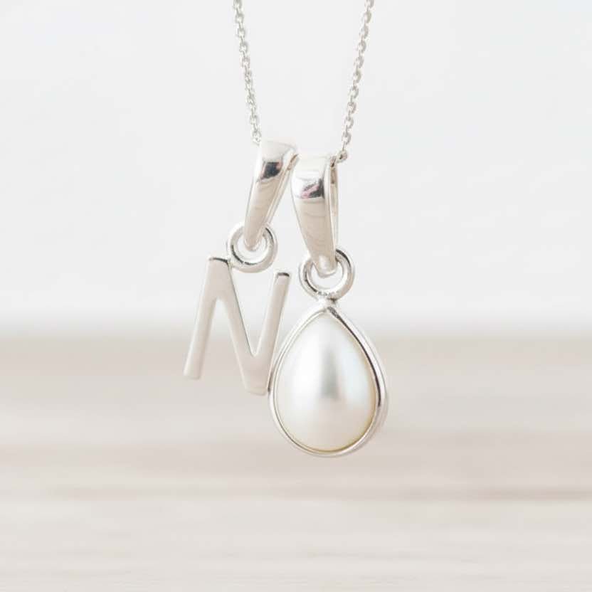 Sterling Silver necklace with a N initial pendant and a teardrop pearl pendant on a white background