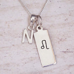 sterling silver initial n leo zodiac star sign pendant necklace against a light wooden background