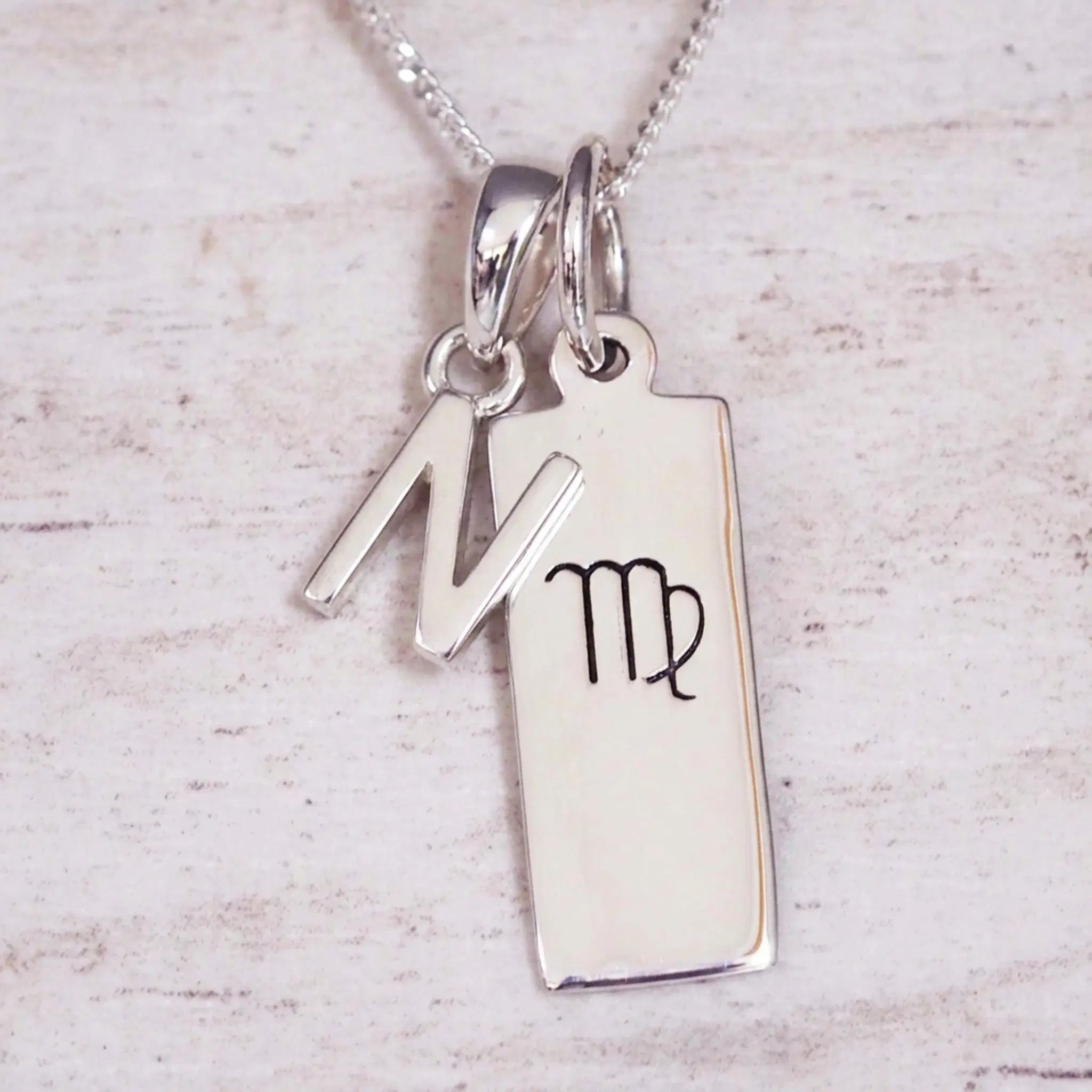 sterling silver initial n virgo zodiac star sign pendant necklace against a light wooden background
