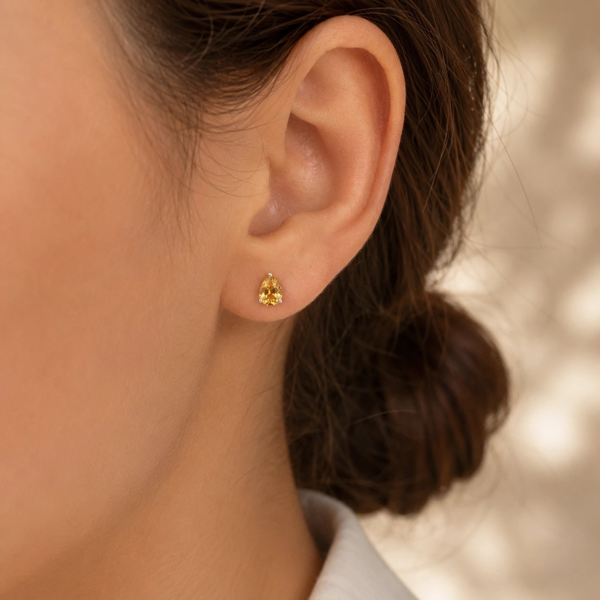 woman with dark brown hair wearing a silver stud claw set faceted natural citrine stud earrings