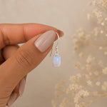sterling silver french hook with faceted rectangle natural moonstone earring being held by fingers