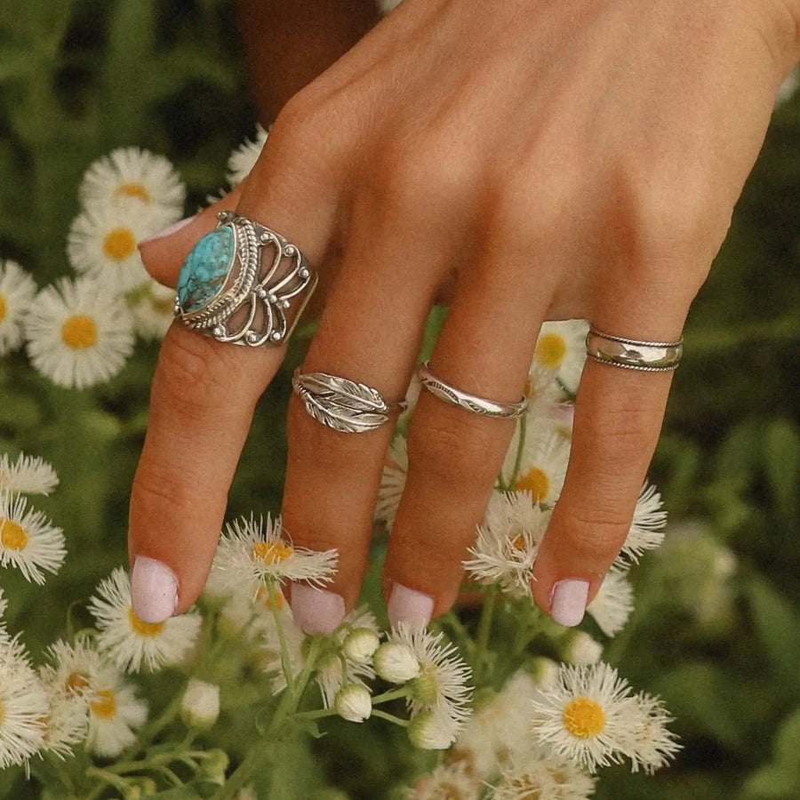 woman with hand over a field of daisies wearing three sterling silver rings - Sterling silver jewellery Australia 