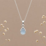 sterling silver november birthstone topaz necklace with a dainty pear-shaped cabochon bezel set natural light blue topaz gemstone hanging