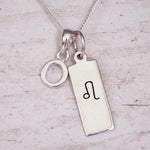 sterling silver initial o leo zodiac star sign pendant necklace against a light wooden background