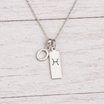 sterling silver O initial Pisces Necklace on a fine silver chain against a light wooden background