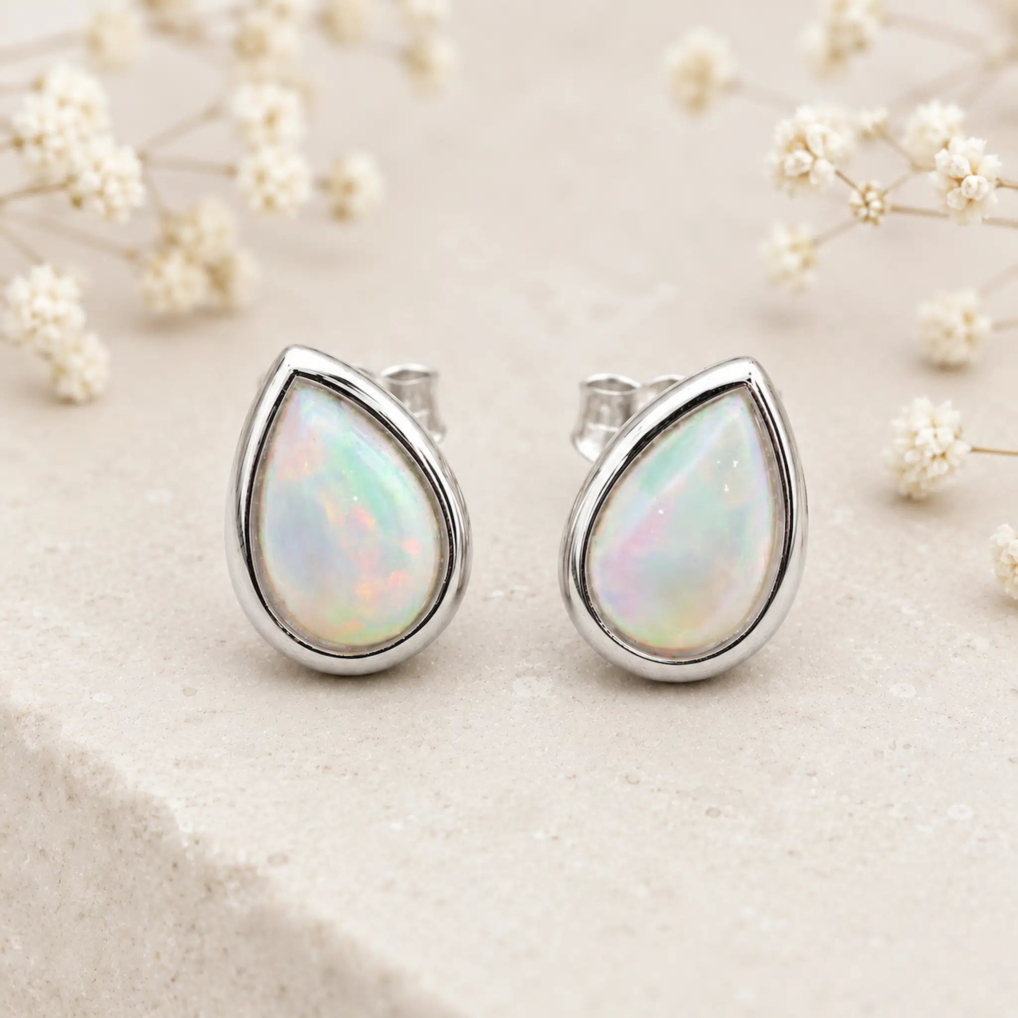 Pair of Sterling Silver October Birthstone Earrings in pear-shaped cabochon stud style with natural opal gemstones on a light surface.