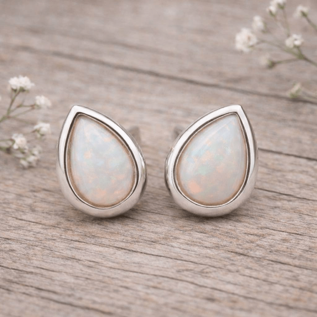 Teardrop-shaped opal earrings with silver setting on a light gray background