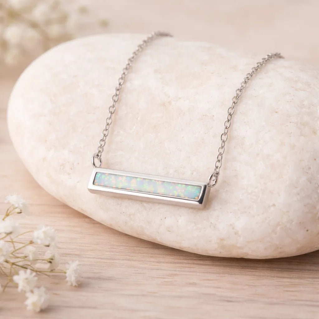 Necklace with a bar pendant featuring opal stones on a textured surface